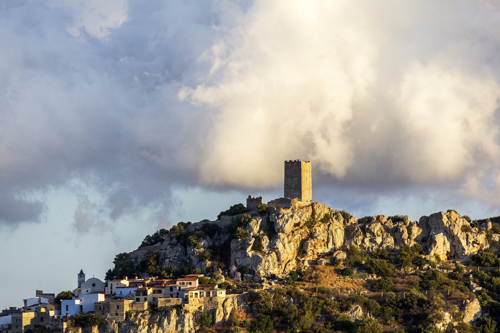 Il Castello della Fava sul colle di Posada, sotto un cielo di nuvoloni