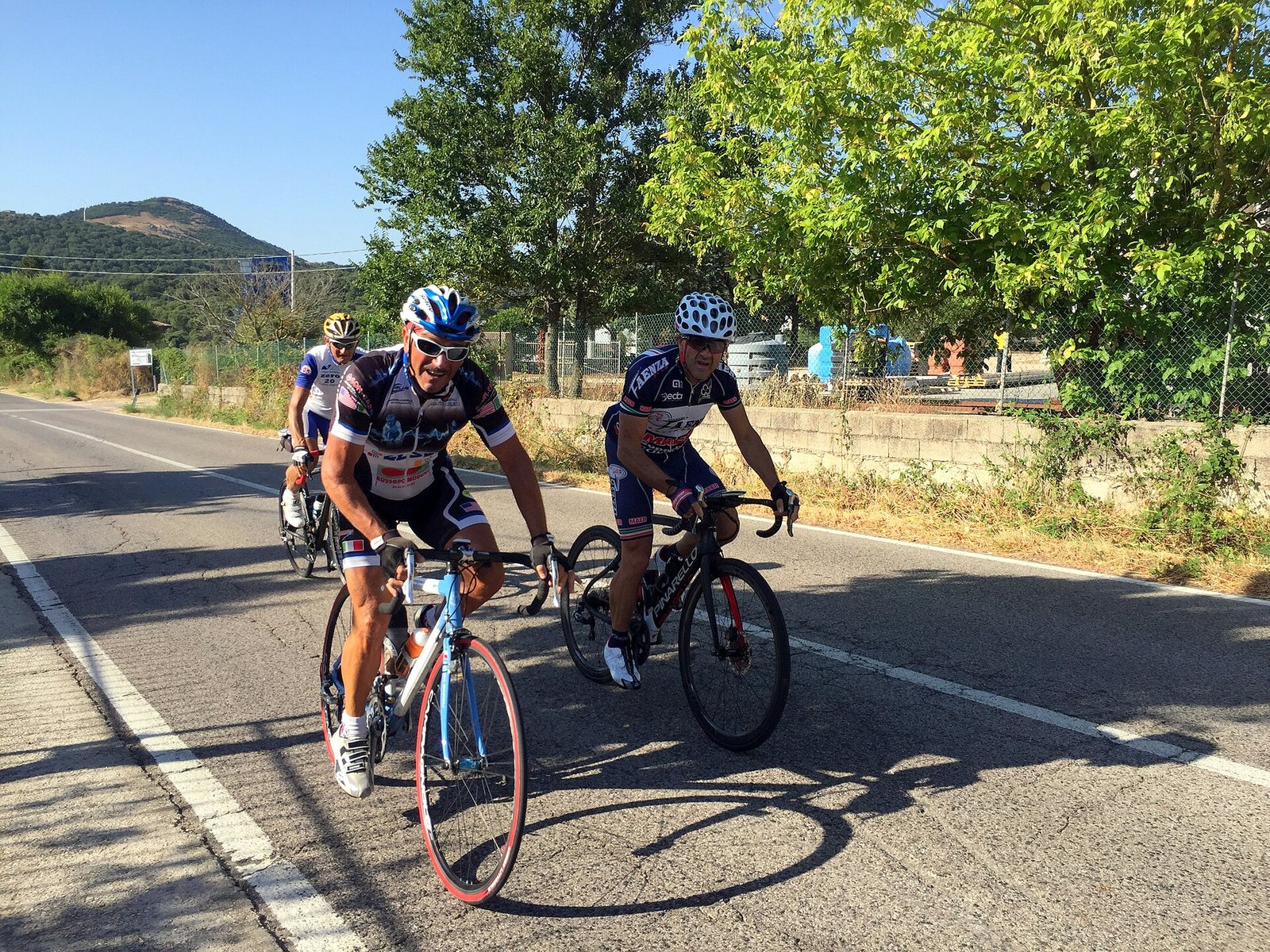 Ciclisti su una strada della Sardegna, tra la macchia e le colline